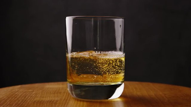 Delicious golden scotch whiskey being poured into glass by barman with perfect ice cubes for a celebration drink