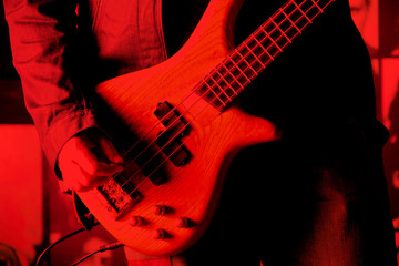 Life style image of close up young man hand, playing electric bass guitar