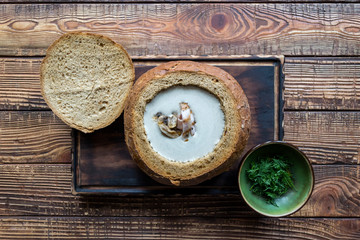 Cream soup in a bread, on a wooden table.