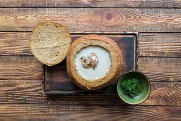 Cream soup in a bread, on a wooden table.