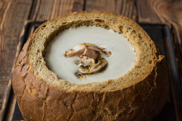 Cream soup in a bread, on a wooden table.