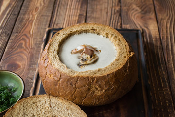 Cream soup in a bread, on a wooden table.