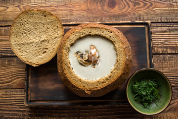 Obraz na płótnie Canvas Cream soup in a bread, on a wooden table.