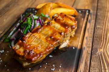 Fried potatoes with grilled meat on a wooden table.