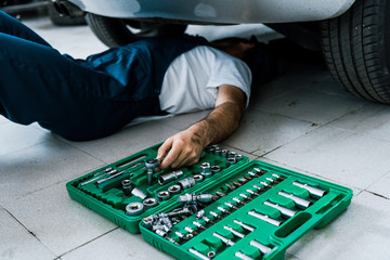 cropped view of car mechanic repairing car in car service