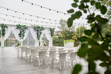 Wedding ceremony with arch, orchid flowers, chairs and bulb in forest outdoors, copy space. Wedding decorations