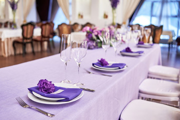 Table setting with white plates, flowers, wineglasses and cutlery on table, copy space. Menu mockup, place setting at wedding reception. Table served for wedding banquet in restauran