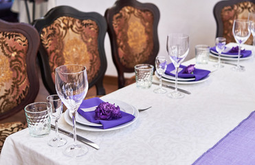 Table setting with white plates, flowers, wineglasses and cutlery on table, copy space. Menu mockup, place setting at wedding reception. Table served for wedding banquet in restauran