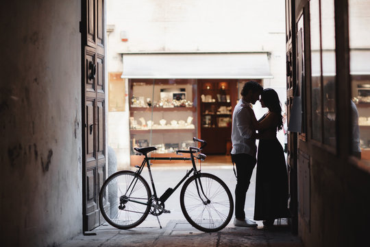 Photo session of love couple. A man and a woman are walking in the old city with a green retro bike