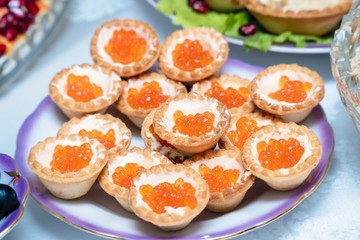 Tartlets with red caviar on a plate.