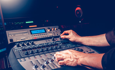 male sound engineer hands mixing a song on professional audio equipment in recording studio