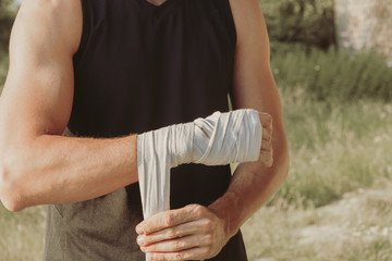 an athlete prepares himself for training wrapping his hands with boxing bandage