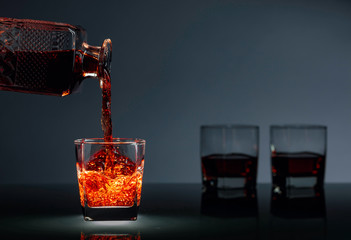 Alcoholic drink pouring from a decanter into a glass.