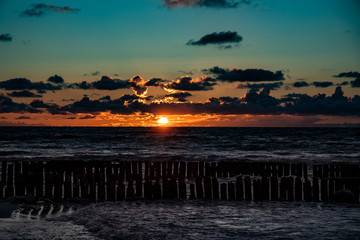 Fototapeta na wymiar colorful sunset over the Polish Baltic sea with dark sky clouds and breakwater
