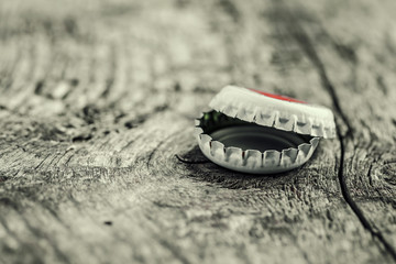 bottle cap from a beer bottle on wooden background. several beer lids lie in pile, behind them bottle. close up. soft selective focus.