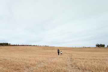 A woman and a boy walking through a field of mown wheat.