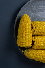 Fresh cooked yellow corn cobs lie on a gray dish