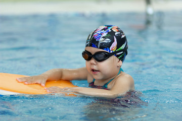 Little girl with float board in the swimming pool