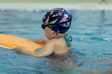 Little girl with float board in the swimming pool