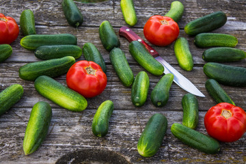 Fresh cucumbers tomatoes and peppers on an old wooden table
