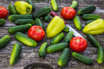 Fresh cucumbers tomatoes and peppers on an old wooden table