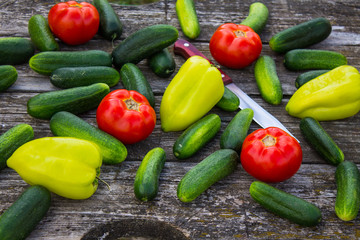Fresh cucumbers tomatoes and peppers on an old wooden table