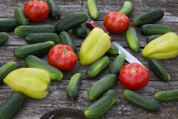 Fresh cucumbers tomatoes and peppers on an old wooden table