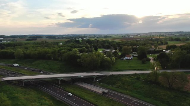 4k Aerial drone footage flying over and panning left of a two lane highway in the rural countryside of Lancaster county, Pennsylvania during sunset