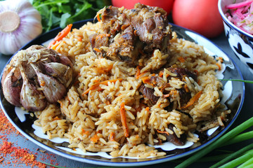 Pilaf on a platter of meat and spices.pilaf in a plate on a wooden background, top view.  The concept of Oriental cuisine. Homemade Uzbek pilaf of lamb is served in cast iron cookware. Copy space.P