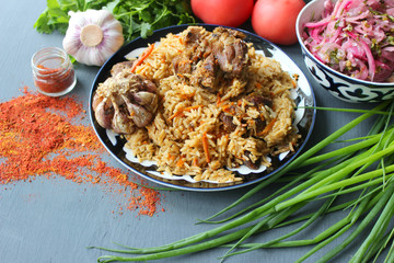 Pilaf on a platter of meat and spices.pilaf in a plate on a wooden background, top view.  The concept of Oriental cuisine. Homemade Uzbek pilaf of lamb is served in cast iron cookware. Copy space.P