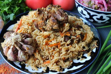 Pilaf on a platter of meat and spices.pilaf in a plate on a wooden background, top view.  The concept of Oriental cuisine. Homemade Uzbek pilaf of lamb is served in cast iron cookware. Copy space.P