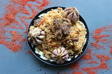 Pilaf on a platter of meat and spices.pilaf in a plate on a wooden background, top view.  The concept of Oriental cuisine. Homemade Uzbek pilaf of lamb is served in cast iron cookware. Copy space.P
