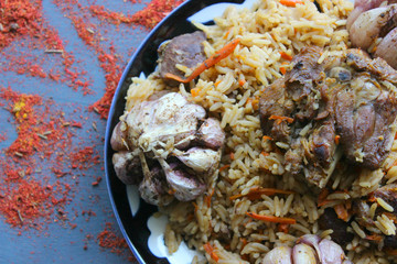 Pilaf on a platter of meat and spices.pilaf in a plate on a wooden background, top view.  The concept of Oriental cuisine. Homemade Uzbek pilaf of lamb is served in cast iron cookware. Copy space.