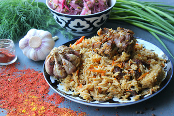 Pilaf on a platter of meat and spices.pilaf in a plate on a wooden background, top view.  The concept of Oriental cuisine. Homemade Uzbek pilaf of lamb is served in cast iron cookware. Copy space.