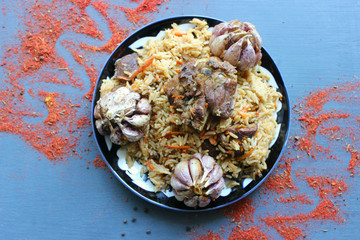Pilaf on a platter of meat and spices.pilaf in a plate on a wooden background, top view.  The...