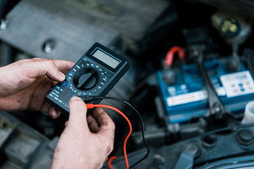 cropped view of car mechanic holding measuring device in car service