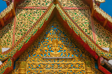 Decorative temple roof with shadow of adjacent chedi on the front in Chiang Mai Thailand.