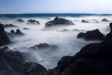 Larga exposición de rocas en el mar con efecto de humo. Misterio y niebla