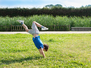 Young boy doing a somersault on a green park