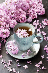 Still life with tea cup and lilac on  dark  background