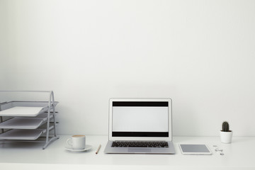 office table on which laptop, coffee, tablet, camera and other items