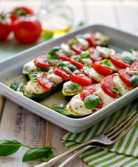 Vegetarian food, Zucchini with the addition of tomatoes, mozzarella, basil and olive oil (caprese salad) in a ceramic baking dish, top view. Stuffed courgettes ready for baking