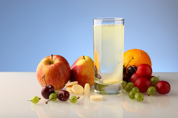 Effervescent soluble tablet of vitamins in a glass with water. Various fruits, a set of vitamins.