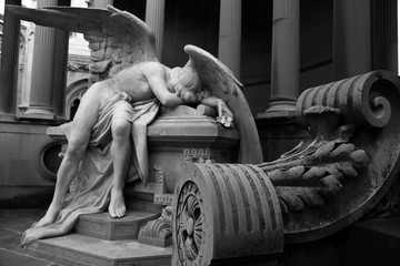 Estatua de ángel sobre tumba. Melancolía y tristeza. Blanco y negro en mausoleo