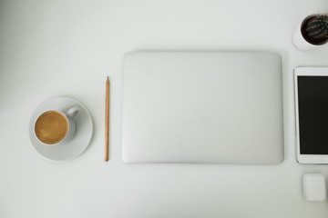 office table on which laptop, coffee, tablet, camera and other items