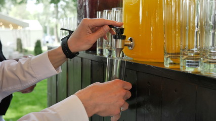Fresh organic chilled orange lemonade for a big company at a party poured into a glass