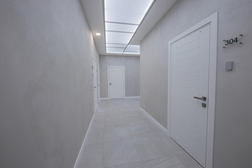 a corridor in an office building with a large number of meeting rooms without furniture