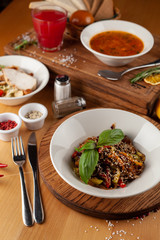 Side view of thai buckwheat noodles with vegetables and sesame, flavoured with oyster sauce on a wooden table with ingredients
