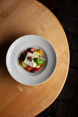 Top view of a greek vegetable salad with a huge chunk of feta cheese for diet dinner indoors