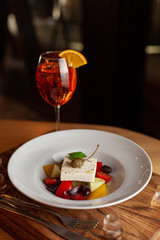 Refreshing summer cocktail Aperol Spritz and greek salad with feta cheese as a fancy dinner in a restaurant